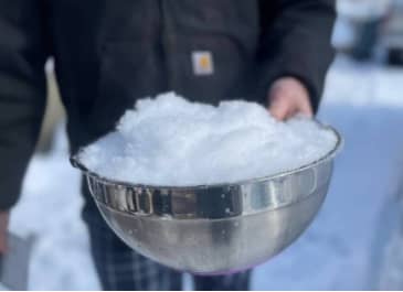 a person holding a bowl of fresh, fluffy snow